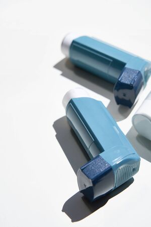 Many Asthma inhalers on white, with sharp shadows