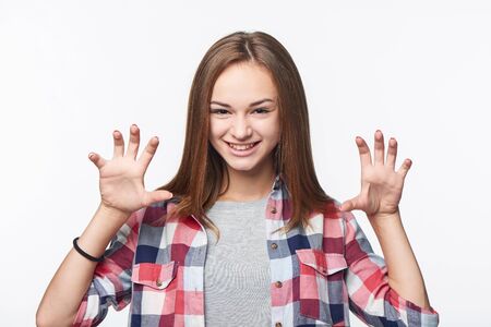 Teen girl growling at you and gesturing a claw shape with her hands, studio portrait over white backgroundの写真素材