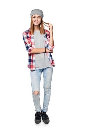 Smiling relaxed teen girl standing in full length, looking at camera, studio portraitの写真素材