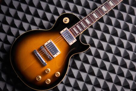 Sunburst electric guitar lying on acoustic foam panel background, flat layの写真素材