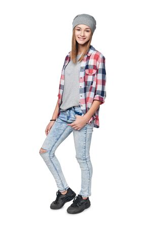 Smiling relaxed teen girl standing in full length, looking at camera, studio portraitの写真素材