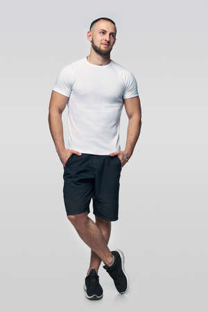 Full length man dressed in shorts and white t-shirt standing casually looking to side at blank copy spaceの写真素材