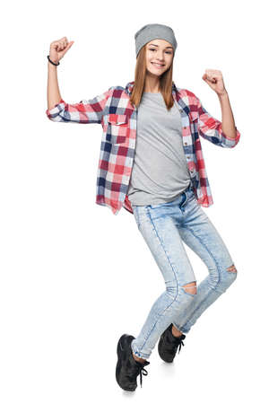 Smiling teen girl standing in full length on tiptoe gesturing success, looking at camera, studio portraitの写真素材