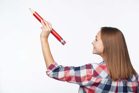 Profile of a teen girl writing with big pencil on blank copy spaceの写真素材