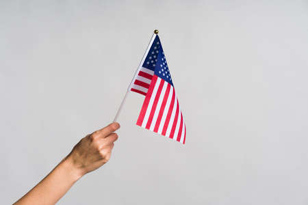 Human hand holding USA flag, over grey backgroundの写真素材