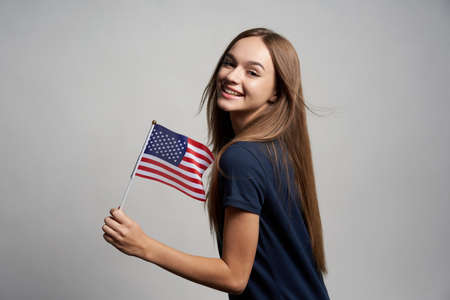 Happy female holding America flag, over grey backgroundの写真素材