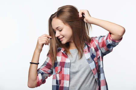 Smiling relaxed teen girl with raised hands looking down, studio portraitの写真素材