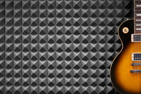 Sunburst electric guitar on acoustic foam panel background, copy space on leftの写真素材