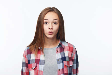 Excited surprised teen girl looking at camera with widely opened eyes, studio portraitの写真素材