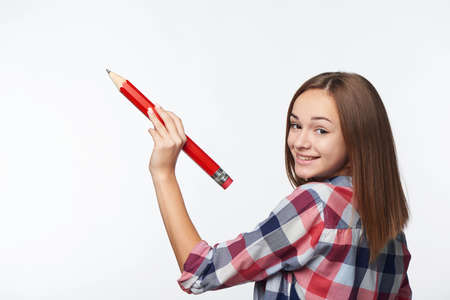 Teen girl writing on copy space. Casual teen girl holding big pencil and drawing or writing on blank copy space for textの写真素材