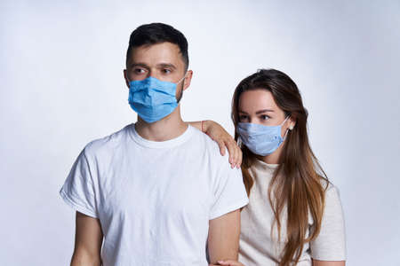 Young couple wearing medicine masks standing looking to side at blank copy spaceの写真素材