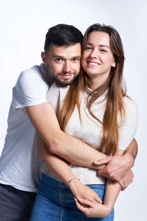 Attractive young couple hugging looking at camera smiling
