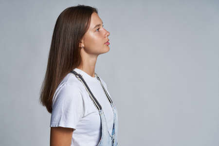 Closeup profile portrait of a teen gir looking forward, over grey backgroundの写真素材