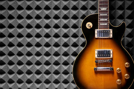 Sunburst electric guitar on acoustic foam panel background, copy space on leftの写真素材