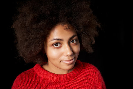 Closeup of smiling mixed race African-Caucasian girlpeeking in camera, over black background. Wide angle portraitの写真素材