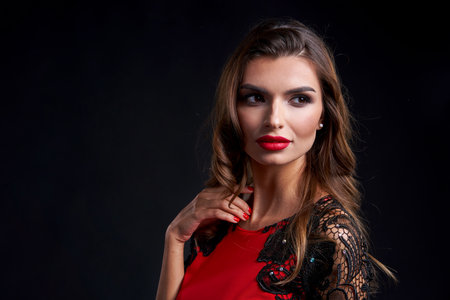 Closeup of mysterious gorgeous woman in party dress and red lips makeup looking to side, over dark backgroundの写真素材
