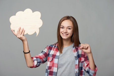 Joyful girl holding thinking bubble and gesturing victory gestureの写真素材