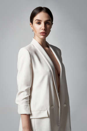 Fashion portrait of beautiful brunette woman in white jacket, studio shotの写真素材
