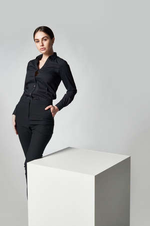 Stylish woman in black shirt and pants standing by white boxの写真素材