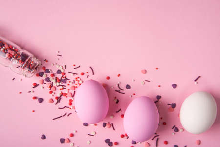 White and pink Easter eggs and bakery decoration scattered on pink backgroundの写真素材
