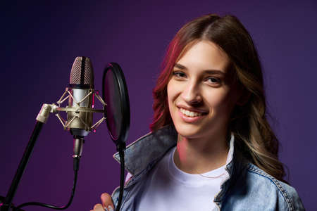 Girl blogger recording audio podcast. Happy smiling girl with microphoneの写真素材