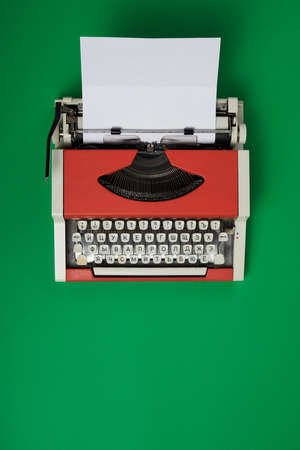 Top view of red vintage typewriter with white blank paper sheetの写真素材