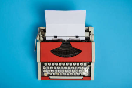 Top view of red vintage typewriter with white blank paper sheetの写真素材