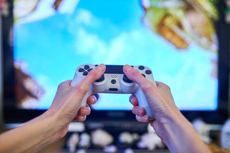 Kids hands playing video game with joystick, monitor screenの写真素材