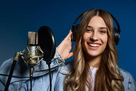 Girl blogger recording audio podcast. Happy smiling girl with microphone with headphone on her headの写真素材