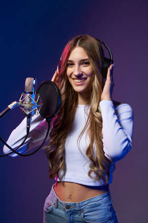 Girl blogger recording audio podcast. Happy smiling girl with microphone with headphone on her headの写真素材