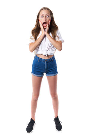 Full length of shocked teen standing over white background shouting looking to sideの写真素材