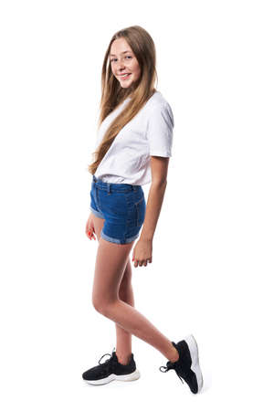 Full length of casual teen girl wearing white t-shirt and denim shorts posing over white backgroundの写真素材
