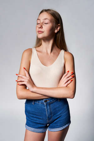 Portrait of calm teen girl with freckles posing with closed eyes and folded handsの写真素材