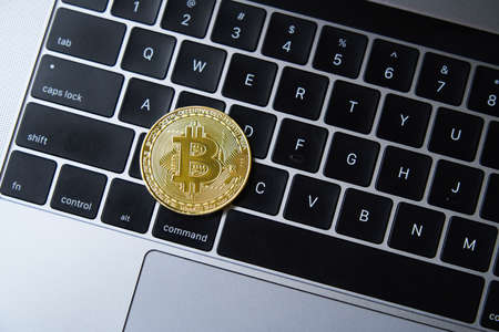 Golden bitcoin coin on laptop keyboardの写真素材