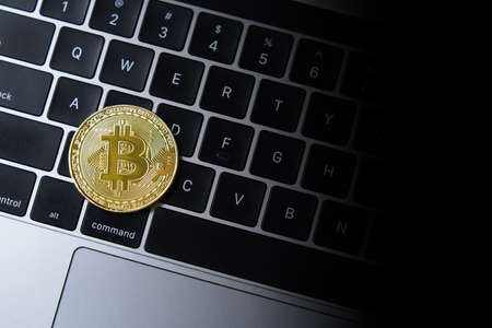 Golden bitcoin coin on laptop keyboardの写真素材