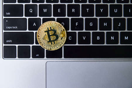 Golden bitcoin coin on laptop keyboard