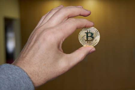 Human hand holding showing a golden bitcoin coinの写真素材
