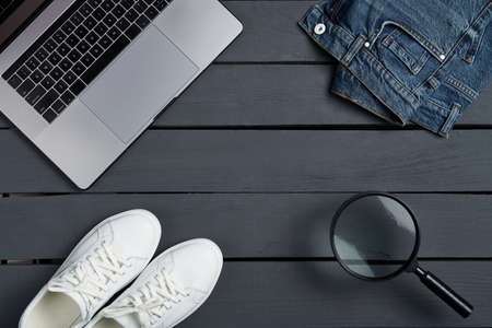 Template top view laptop shoes, jeans and magnifying glass over rough wooden planks, copy space for text or product in centerの写真素材