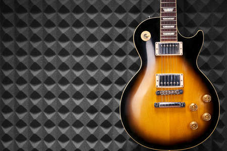 Sunburst electric guitar standing over acoustic foam panel backgroundの写真素材