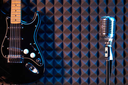 Studio condenser microphone and black electric guitar