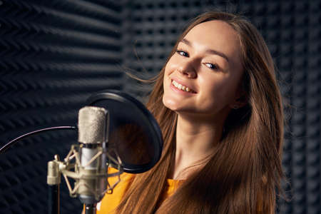 Teen girl in recording studio with mic over acoustic panel backgroundの写真素材