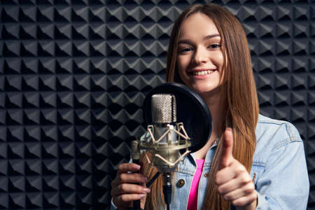 Teen girl in recording studio with mic over acoustic panel backgroundの写真素材