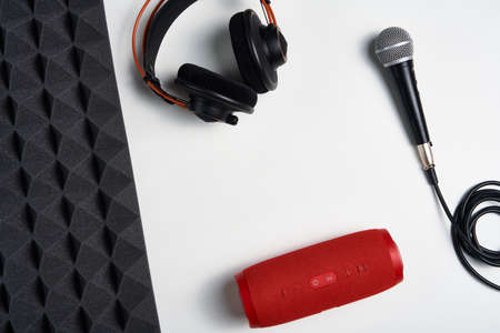 Music, blogging concept background. Microphone, headphones and portable stereo speaker on on white background with copy space and acoustic foam panel, flat layの写真素材
