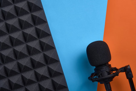 Flat lay of microphone and acoustic foam panel, over blue and orange background, with copy spaceの写真素材