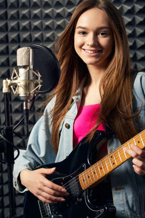 Girl musician in recording studio playing electric guitarの写真素材