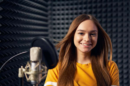 Teen girl in recording studio with mic over acoustic panel backgroundの写真素材