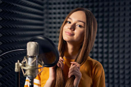 Teen girl in recording studio with mic over acoustic panel backgroundの写真素材