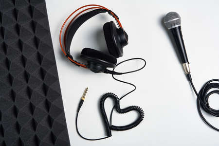 Microphone, headphones and heart shaped cable on on white background with acoustic foam panel on sideの写真素材