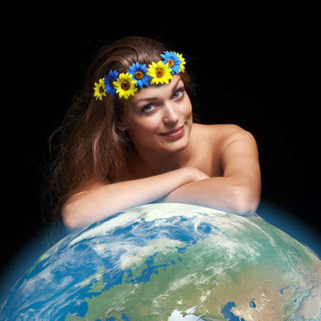 Female wearing flower yellow and blue wreath, leaning on Earth globeの写真素材