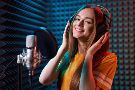 Teen girl in recording studio with mic over acoustic absorber panel backgroundの写真素材